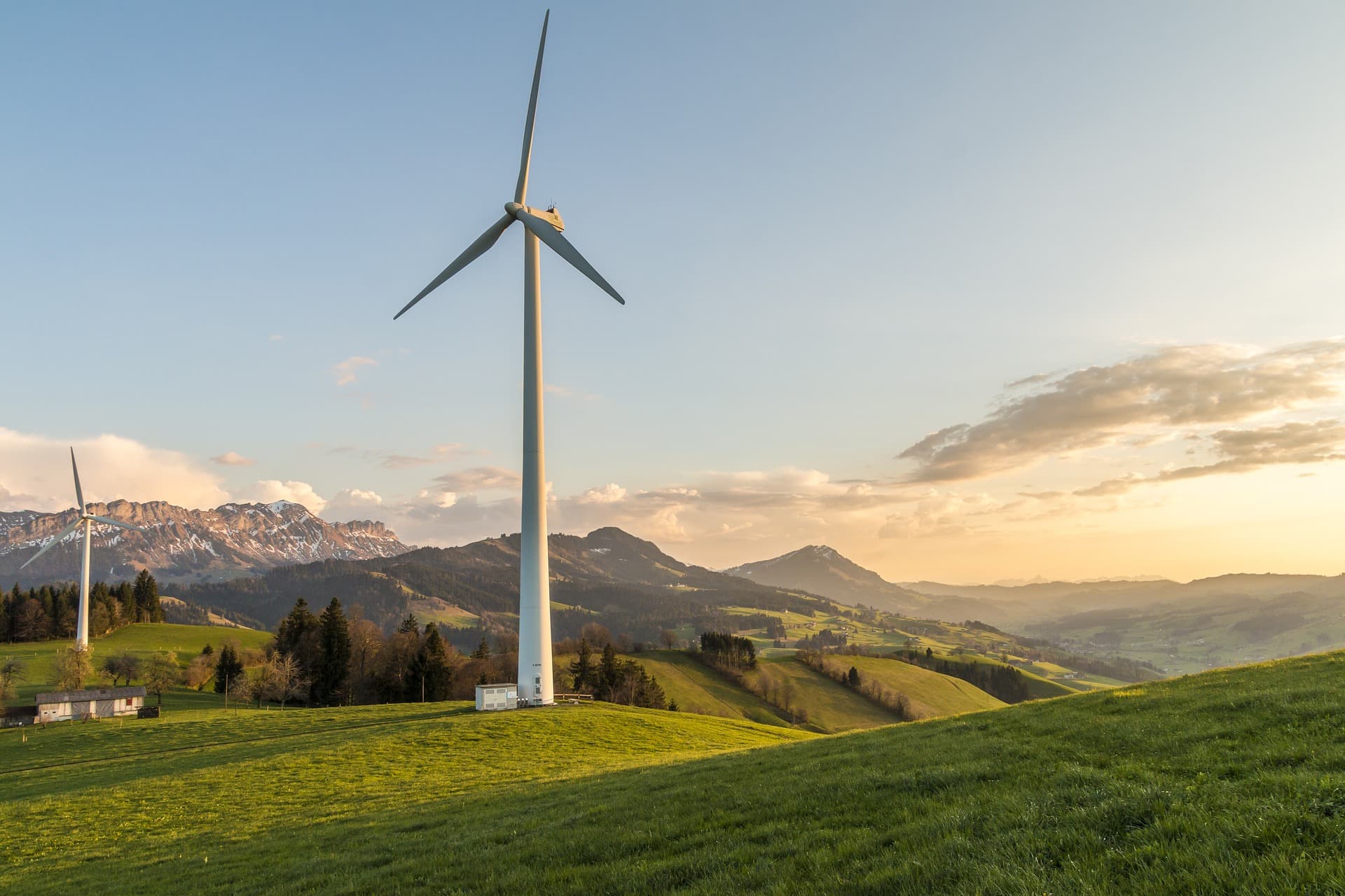 Wind turbines on green alpine hills at golden hour